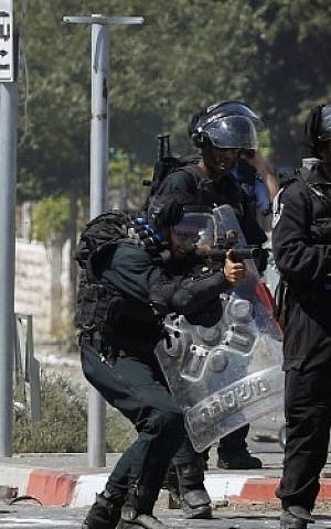 An Israeli border police officer fires a tear gas canister towards masked Palestinian protesters during clashes in the Shuafat neighborhood in East Jerusalem, on July 3, 2014. (Photo credit: Sliman Khader/FLASH90) 