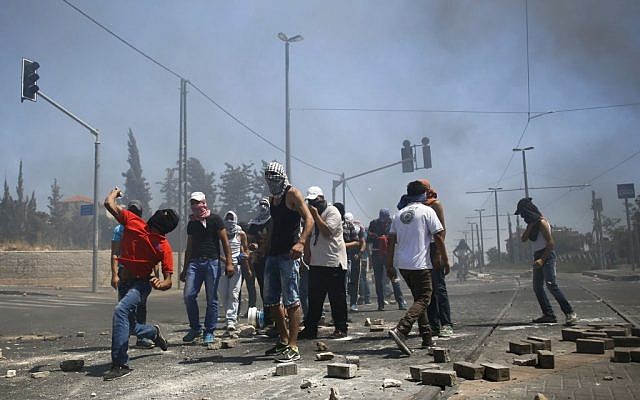 Masked Palestinian protesters throw stones towards Israeli police (unseen) during clashes in the Shuafat neighborhood in East Jerusalem, on July 3, 2014 (Photo credit: Sliman Khader/FLASH90)