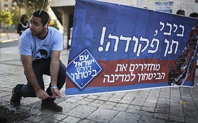 File: An activist with the right-wing Im Tirzu organization putting up a sign in Jerusalem calling on Benjamin Netanyahu to act to stop Gazan rocket fire, on Monday, July 7, 2014. (photo credit: Hadas Parush/Flash90)