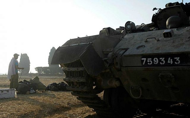 An IDF soldier prays by an armored personnel carrier near the Gaza border in southern Israel on the first day of Operation Protective Edge, July 8, 2014. (photo credit: David Buimovitch/Flash90)