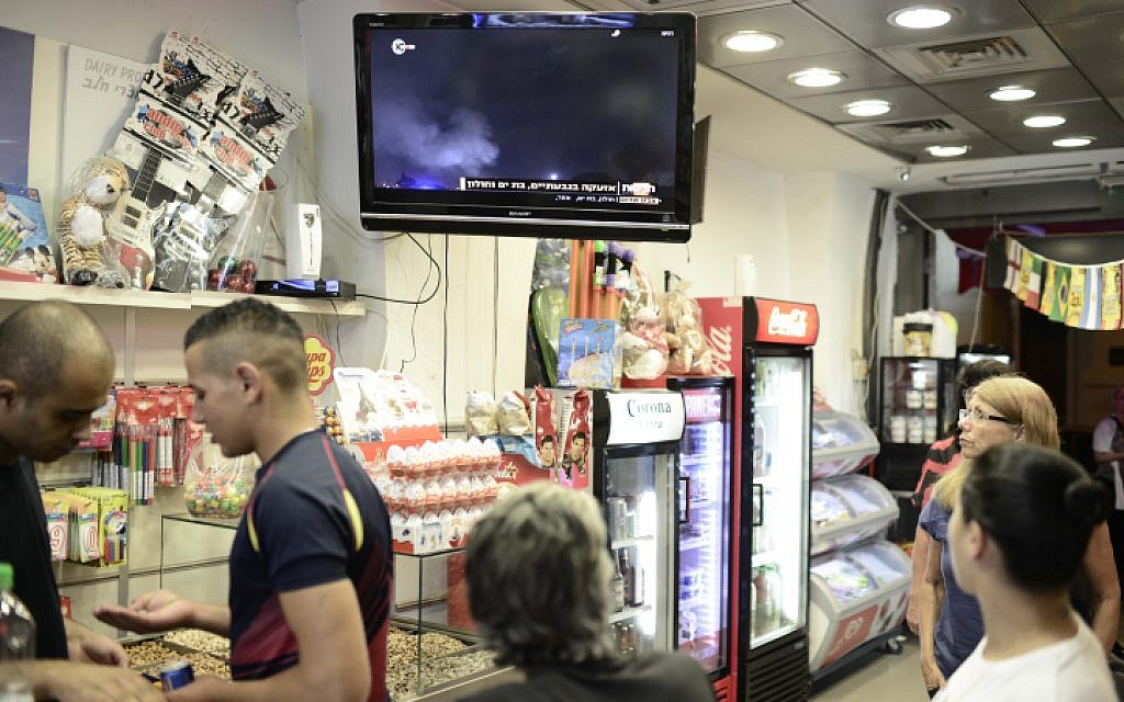Shoppers watch TV broadcasts about the offensive Israel launched against the Gaza Strip, with a series of airstrikes in response to increasing rocket attacks fired into Israel. July 08, 2014. (photo credit: Tomer Neuberg/Flash90)