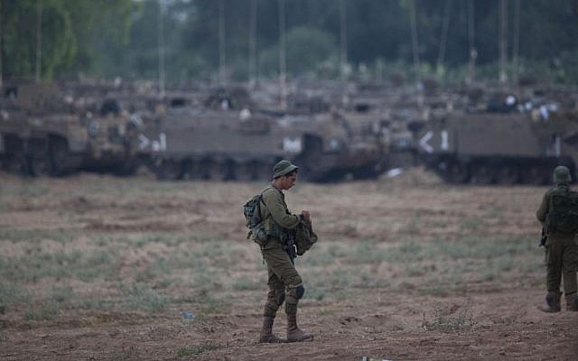 A soldier stands in a field near the Gaza border with IDF APCs (Armed Personnel Carriers) in the background, Wednesday, July 9, 2014. (photo credit: Yonatan Sindel/Flash90) A soldier stands in a field near the Gaza border with IDF APCs (Armed Personnel Carriers) in the background, Wednesday, July 9, 2014. (photo credit: Yonatan Sindel/Flash90)