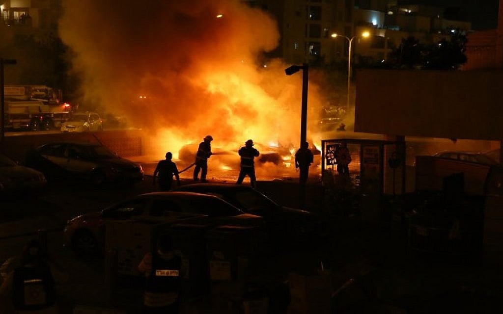 Fire fighters and police units were on the scene of an explosion in Ashdod caused by rocket fire from Gaza, on the third day of Operation Protective Edge, July 10, 2014. The rocket had landed on a car, crushing it, and causing the building's gas tank to explode and burst into flames. (Photo credit: Flash90)