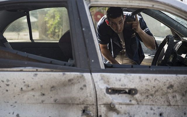 A man takes his belongings out of his car, which sustained severe damaged after a rocket landed on in near Sderot, southern Israel, on Thursday July 10, 2014, the third day of Operation Protective Edge. (photo credit: Hadas Parush/Flash90)