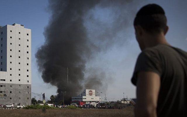 An Israeli watches smoke rise from a gas station in Ashdod that was hit directly by rocket fire from Gaza on the fourth day of Operation Protective Edge, Friday, July 11, 2014. (photo credit: Hadas Parush/Flash90)