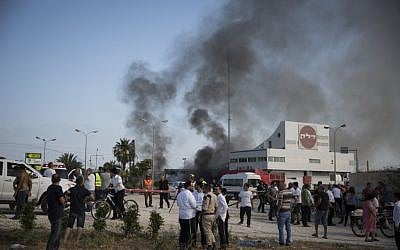 Israelis watch the smoke rising from a gas station in Ashdod that was hit directly by rocket fire from Gaza on the fourth day of Operation Protective Edge, July 11, 2014. The rocket caused explosions and three people were injured, one of them critically. (Photo credit: Hadas Parush/Flash90)