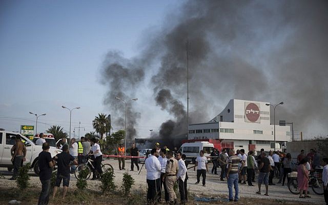 Israelis watch the smoke rising from a gas station in Ashdod that was hit directly by rocket fire from Gaza on the fourth day of Operation Protective Edge, July 11, 2014. The rocket caused explosions and three people were injured, one of them critically. (Photo credit: Hadas Parush/Flash90)