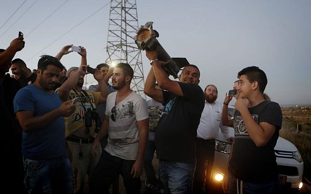 Residents of Sderot looking at a piece of a rocket that fell in an open field (photo credit: Miriam Alster/Flash 90)