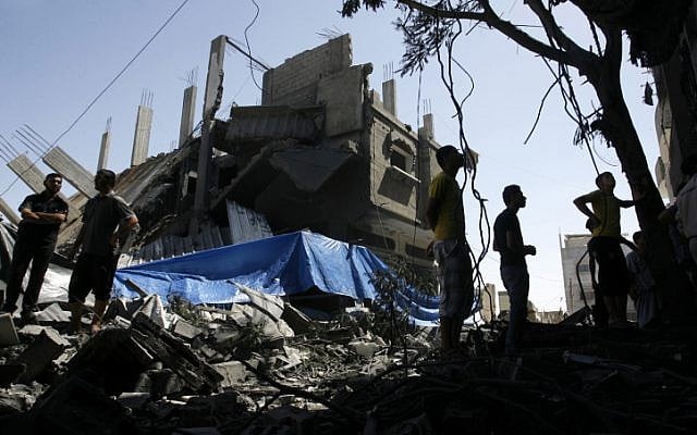 Palestinians seen walking among the rubble of a destroyed house following an Israeli missile strike, in Rafah on July 14, 2014. (photo credit: Abed Rahim Khatib/Flash90)
