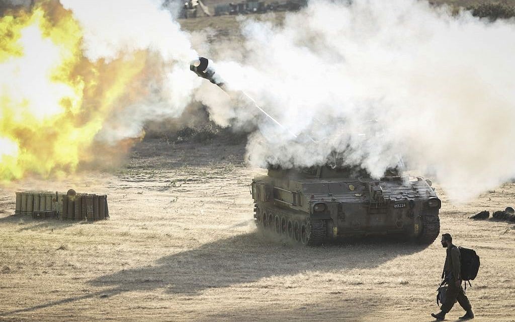 An Israeli soldier walks past an artillery cannon as it fires a shell to the Gaza Strip from a temporary base set up near the border, Monday, July 14, 2014 (photo credit: Hadas Parush/Flash90)