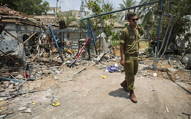 An Israeli soldier looks at the damage to a house following a rocket attack from the Gaza Strip on the town of Yehud, near Ben Gurion Airport, on July 22, 2014. (photo credit: Yonatan Sindel/Flash90)