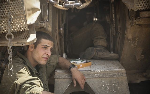 An Israeli soldier rests a moment outside his tank on Friday in a staging area by the Gaza Strip. (Hadas Parush/FLASH90) An Israeli soldier rests a moment outside his tank on Friday in a staging area by the Gaza Strip. (Hadas Parush/FLASH90)