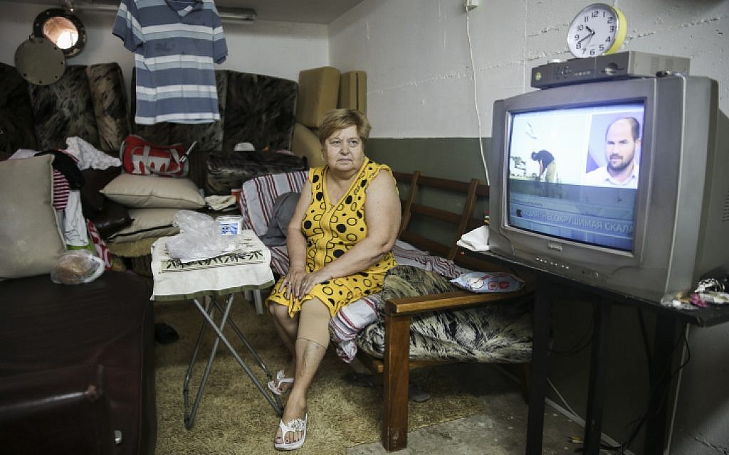 Olga, an immigrant from the former USSR, watches the news in the bomb shelter she has made into her temporary home, in Ashkelon, Southern Israel, on July 30, 2014 (photo credit: Hadas Parush/Flash90)