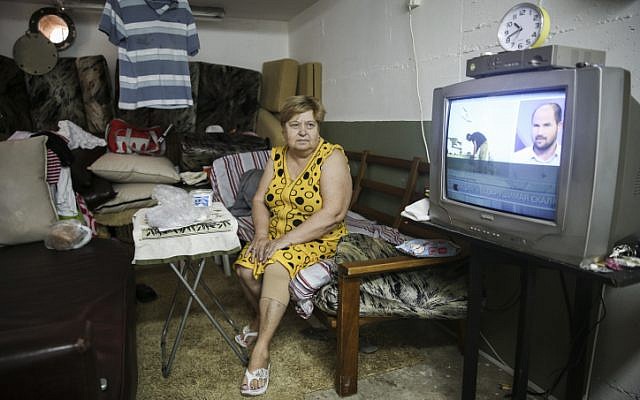 Olga, an immigrant from the former USSR, watches the news in the bomb shelter she made into a temporary home, in Ashkelon, southern Israel, on July 30, 2014 (photo credit: Hadas Parush/Flash90) 