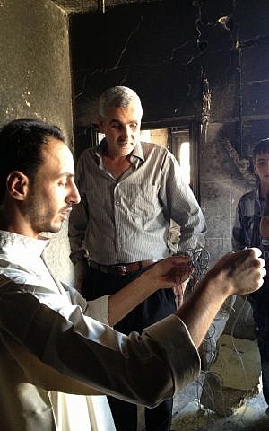 Hebron residents in the home of suspected kidnapper Amer Abu Eysha. IDF soldiers entered the home late Monday night and detonated Amer's apartment in the second floor of the family house. Local activist Murad Amer holds up the detonating wire used by the IDF. Hebron was quiet on Tuesday, after the Israeli soldiers left the city and redeployed on its outskirts. (photo credit: Elhanan Miller / Times of Israel)