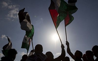 In this Friday, March 30, 2012, file photo, Arab Israeli protesters wave Palestinian flags as they gather to mark the annual Land Day event in the Arab Village of Dir Hana, northern Israel. (Photo credit: AP/Ariel Schalit)
