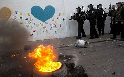 In this Saturday, July 5, 2014, file photo, Israeli riot police officers take positions during clashes with youths at the northern Arab Israeli town of Ar'ara, as violence spread from Jerusalem to Arab towns in northern Israel, following the funeral of an Arab teenager who was killed by Israeli extremists in a revenge attack for the kidnapping and murder of three Israeli teenagers in June. (Photo credit: AP/Oded Balilty)