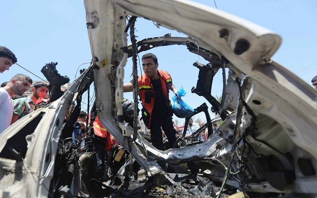 Palestinians gather around a car wreckage after an airstrike in Jabalya refugee camp in the north of the Gaza Strip, Thursday, July 10, 2014. (AP Photo/Hatem Moussa)