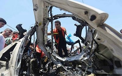 Palestinians gather around a car wreckage after an airstrike in Jabalya refugee camp in the north of the Gaza Strip, Thursday, July 10, 2014. (AP Photo/Hatem Moussa)