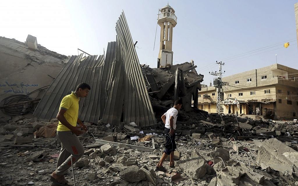 Palestinians gather around the ruins of the Al-Tawfeeq mosque after it was hit by an Israeli missile strike in the Nuseirat refugee camp, central Gaza Strip, Saturday, July 12, 2014. Israeli airstrikes overnight targeting Hamas in Gaza hit the mosque, which Israel said concealed weapons. (photo credit: AP Photo/Hatem Moussa)
