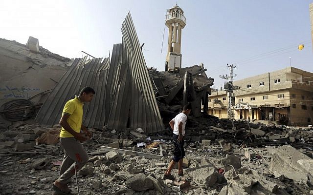 Palestinians gather around the ruins of the Al-Tawfeeq mosque after it was hit by an Israeli missile strike in the Nuseirat refugee camp, central Gaza Strip, Saturday, July 12, 2014. Israeli airstrikes overnight targeting Hamas in Gaza hit the mosque, which Israel said concealed weapons. (photo credit: AP Photo/Hatem Moussa)
