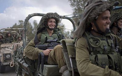 IDF soldiers smile as they ride on a military vehicle near the Israel-Gaza Border, Thursday, July 17, 2014. (Photo credit:AP/Ariel Schalit)