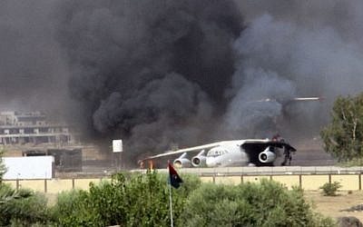 In this Saturday, July 26, 2014 screenshot from video obtained from a freelance journalist traveling with the Misarata brigade, shows an airplane on the tarmac of the airport belching black smoke into the air during fighting between the Islamist Misarata brigade and a powerful rival militia, in Tripoli, Libya.  (photo credit: AP/AP video)