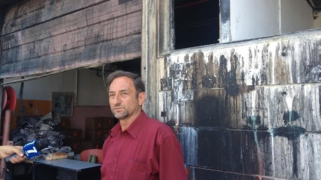 The owner of the Denber paint factory speaking on the backdrop of the factory, which was set aflame last Saturday (photo credit: Mitch Ginsburg/Times of Israel) The owner of the Denber paint factory speaking on the backdrop of the factory, which was set aflame last Saturday (photo credit: Mitch Ginsburg/Times of Israel)