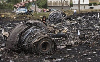 A woman walks at the site of a crashed Malaysia Airlines passenger plane near the village of Rozsypne, eastern Ukraine Friday, July 18, 2014.  (Photo credit: AP/Dmitry Lovetsky)