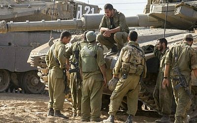 Israeli soldiers next to a Merkava tank stationed at an army deployment area near Israel's border with the Gaza Strip, on July 24, 2014. (photo credit: AFP/Jack Guez)