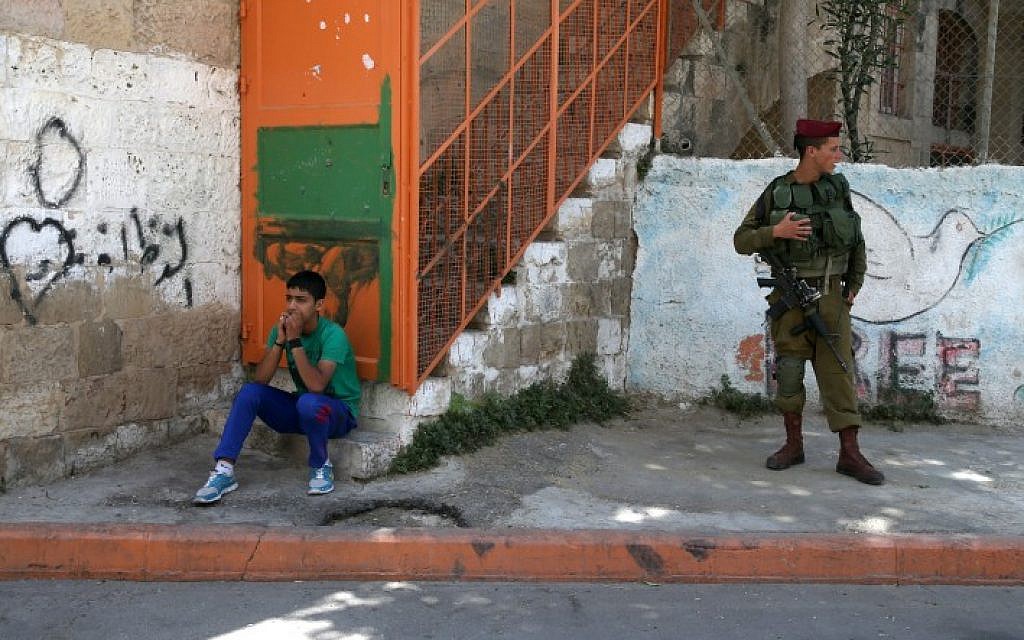 A Palestinian boy sits near Israeli soldiers deployed in the divided West Bank city of Hebron, on the first Friday of the Muslim month of Ramadan. July 04, 2014. (Photo credit: Nati Shohat/FLASH90) A Palestinian boy sits near Israeli soldiers deployed in the divided West Bank city of Hebron, on the first Friday of the Muslim month of Ramadan. July 04, 2014. (Photo credit: Nati Shohat/FLASH90)