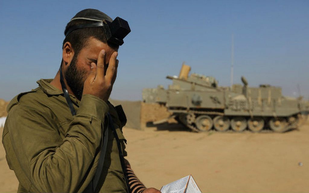 An Israeli soldier prays at an IDF staging area near the Israeli border with Gaza, on July 31, 2014 (photo cropped: Yaakov Naumi/FLASH90)