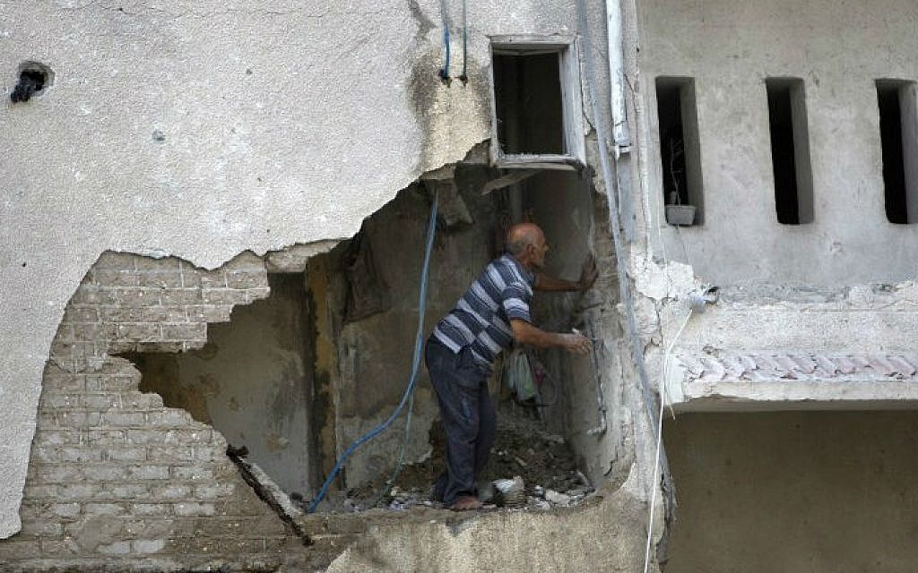 A Palestinian man inspects the damage in a building that was partially destroyed following an Israeli air strike on July 19, 2014, in Gaza (photo credit: AFP/ Mahmud Hams)