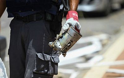A police officer holds the remains of a grad rocket, in the Israeli city of Ashdod, on July 15, 2014 (photo credit: Flash90) 