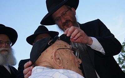Russian Chief Rabbi Berel Lazar putting teffilin on 102-year old David Barulya, a World War II veteran and Crimean Holocaust survivor, at a Holocaust commemoration ceremony in Sevastopol, July 10, 2014. (Cnaan Liphshiz/JTA)