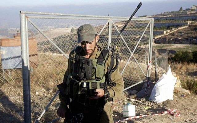 An Israeli soldier patrols near the area where the bodies of three Israeli teenagers were found, in the village of Halhul, near the West Bank city of Hebron, Tuesday, July 1, 2014. (photo credit: AP/Majdi Mohammed)