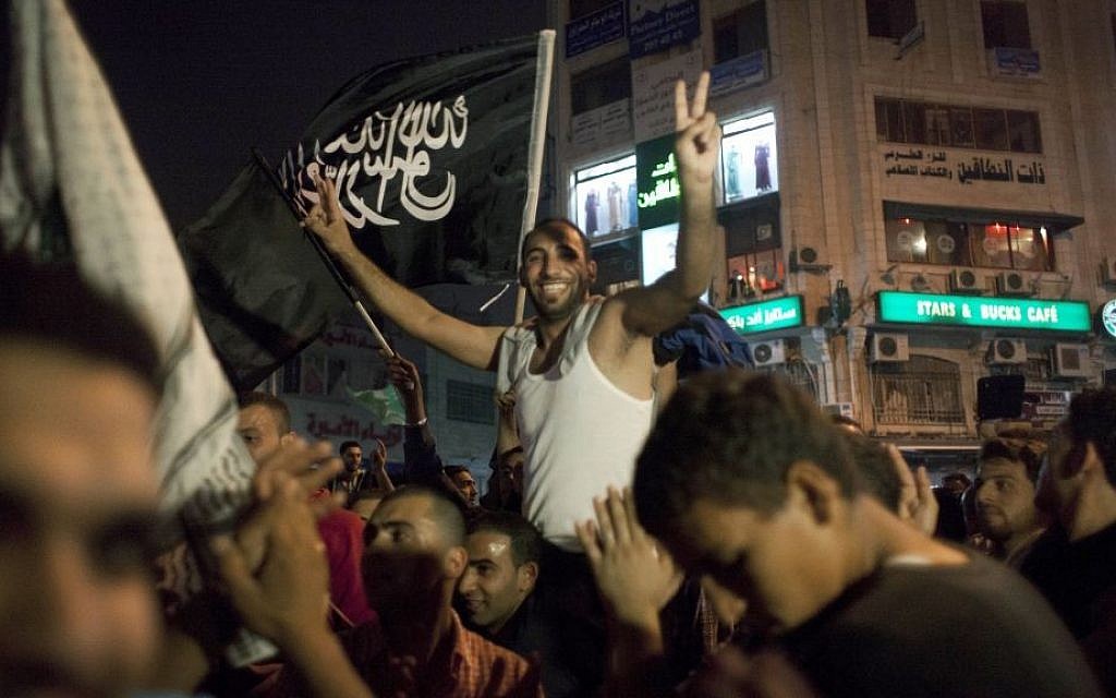 Palestinians dance while flying a Palestinian Islamic Jihad Movement flag reading in Arabic "there is only one God and Muhammad is his prophet," during celebrations in the West Bank city of Ramallah, late Sunday, July 20, 2014. (photo credit: AP Photo/Nasser Nasser) Palestinians dance while flying a Palestinian Islamic Jihad Movement flag reading in Arabic "there is only one God and Muhammad is his prophet," during celebrations in the West Bank city of Ramallah, late Sunday, July 20, 2014. (photo credit: AP Photo/Nasser Nasser)