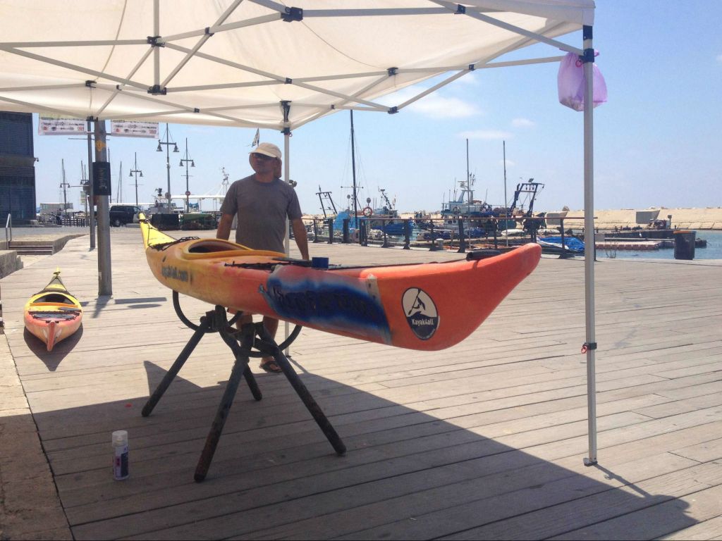 Kayak instructor Roni Levinson is stuck painting his kayaks rather than taking customers out on the water (photo credit: Jessica Steinberg/Times of Israel)