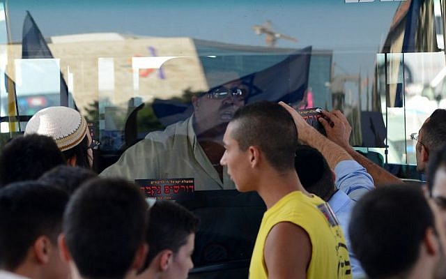 Right-wing protesters bang on a bus and put stickers that call for revenge in front of its Arab bus driver during a large protest in central Jerusalem, on July 1, 2014, in response to the kidnap and murder of three Jewish teens. (photo credit: Mendy Hechtman/Flash90)