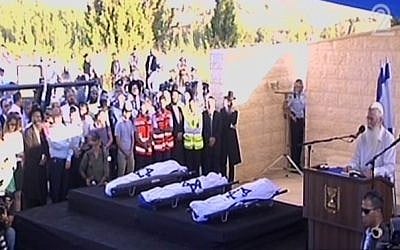 Rabbi Dov Zinger, head of the Mekor Haim yeshiva, delivering a eulogy next to the flag-draped bodies of Naftali Fraenkel, Gil-ad Shaar and Eyal Yifrach at their funeral Tuesday. (Screen capture: Channel 2)