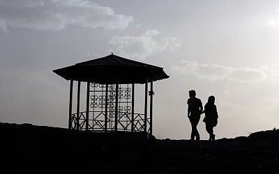An Iranian couple walk together in the northwestern Shahran neighbourhood overlooking Tehran on June 7, 2014. (photo credit: AFP Photo/Atta Kenare)