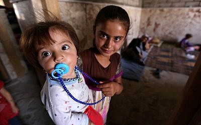 Iraqi Yazidi children who fled the violence in the northern Iraqi town of Sinjar with their family stand at a school where they are taking shelter in the Kurdish city of Dohuk in Iraq's autonomous Kurdistan region, on August 5, 2014 (photo credit: AFP/SAFIN HAMED)