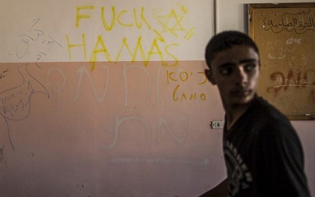 A Palestinian boy walks past writing on a wall allegedly left behind by Israeli soldiers who used the Beit Hanun High school for girls as an advanced base during its military offensive against the Hamas-held Gaza Strip, on August 5, 2014. (photo credit: Marco Longari/AFP)