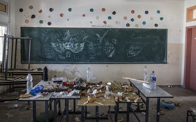 Leftover food seen in a classroom where a military crest and some graffiti in Hebrew are seen on a blackboard after Israeli soldiers withdrew from the Beit Hanun High school for girls, which was reportedly used as an advanced base during Israel's military offensive against the Hamas-held Gaza Strip, on August 5, 2014. (photo credit: Marco Longari/AFP)
