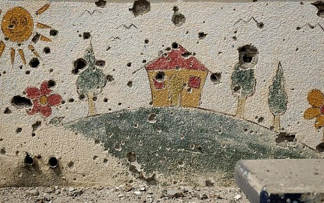Shrapnel holes are seen on a decorated wall in the heavily damaged Sobhi Abu Karsh school in Gaza City's Shejaiya neighborhood on Tuesday, August 5, 2014. (photo credit: Mohammed Abed/AFP)