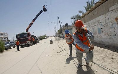 Palestinian electricity company workers drag a power line, many of which were destroyed following an Israeli airstrike in Rafah in the southern Gaza Strip, on August 6, 2014. (photo credit: AFP/SAID KHATIB)