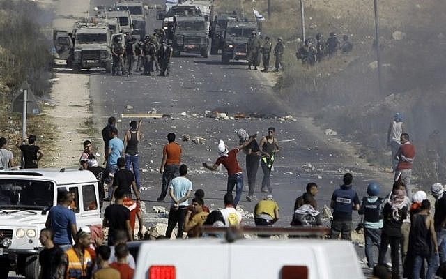 Palestinian protesters clash with Israeli border guards (background) following a demonstration in support of Gaza after Friday prayers in the West Bank town of Bethlehem on August 8, 2014. (photo credit: Musa Al Shaer/AFP)