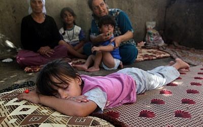 A child sleeps as Iraqi Yazidis, who fled their homes when Islamic State militants attacked the town of Sinjar, sit in a building where they found refuge  in the Kurdish city of Dohuk in Iraq's autonomous Kurdistan region, August 10, 2014. (AFP/Ahmad al-Rubaye)