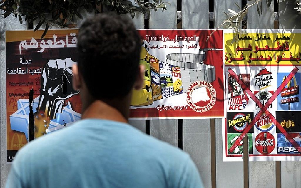 A Palestinian man reads posters calling people to boycott Israeli products and other companies following the latest war between Hamas militants in the Gaza Strip and Israel’s army, on August 12, 2014 in the mostly Arab East Jerusalem . The posters read from L to R: "Boycott them, the campaign for a renewing boycott", "Freedom is a choice, what do you choose?", "Blockade for blockade, boycott them, until they lift the Gaza blockade". (photo credit: AFP/AHMAD GHARABLI)