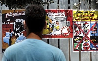 A Palestinian man reads posters calling people to boycott Israeli products and other companies following the latest war between Hamas militants in the Gaza Strip and Israel’s army, on August 12, 2014 in the mostly Arab East Jerusalem . The posters read from L to R: "Boycott them, the campaign for a renewing boycott", "Freedom is a choice, what do you choose?", "Blockade for blockade, boycott them, until they lift the Gaza blockade". (photo credit: AFP/AHMAD GHARABLI)